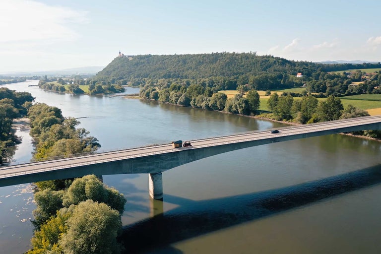 Luftaufnahme einer Brücke über einen Fluss mit Fahrzeugen.