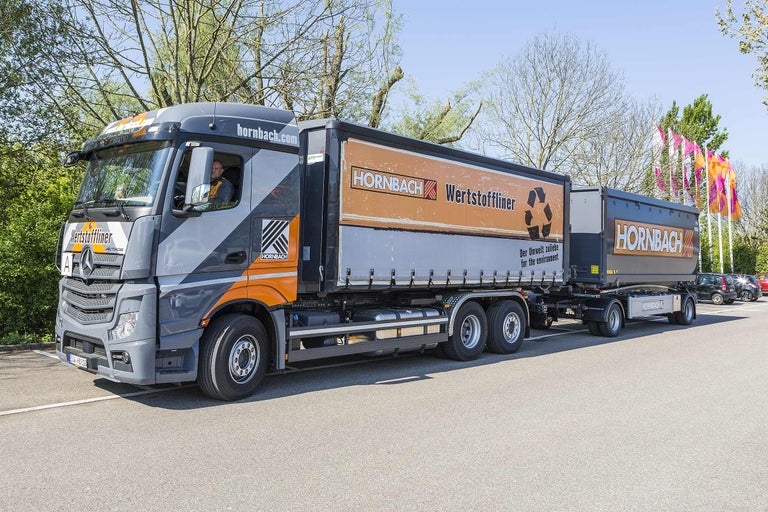 Ein grauer Lastkraftwagen der Marke Hornbach Wertstoffliner auf einem Parkplatz.