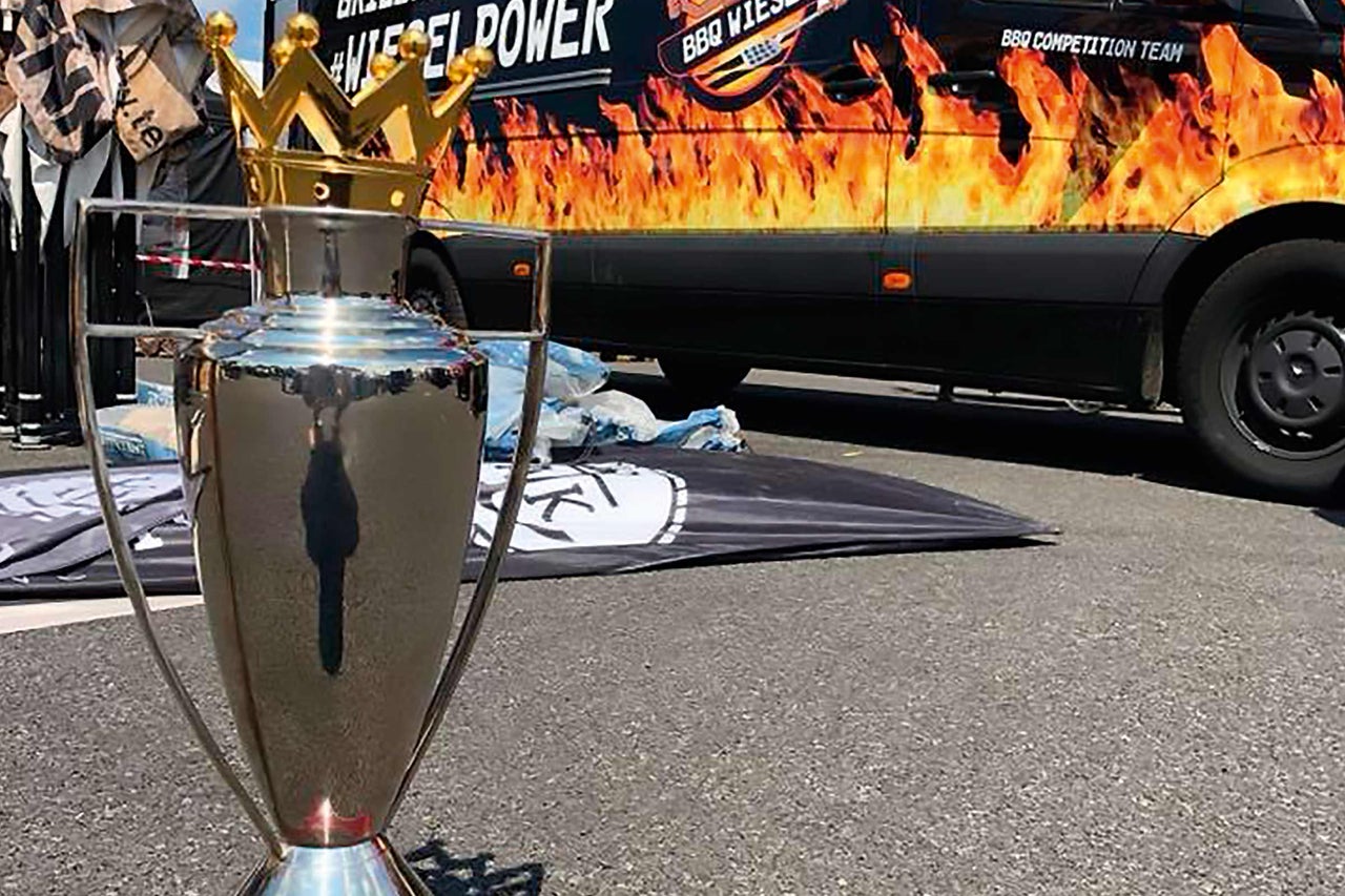 Pokal mit Krone und Fahrzeug mit Grillaufdruck