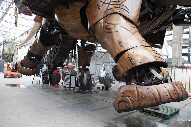 Detailansicht eines großen, hölzernen mechanischen Elefanten mit sichtbaren Metallverbindungen und -mechanismen.