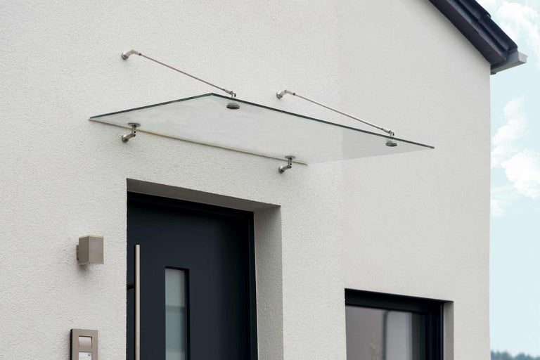 Glasvordach über einer Haustür mit Edelstahlhalterungen an einer Hauswand