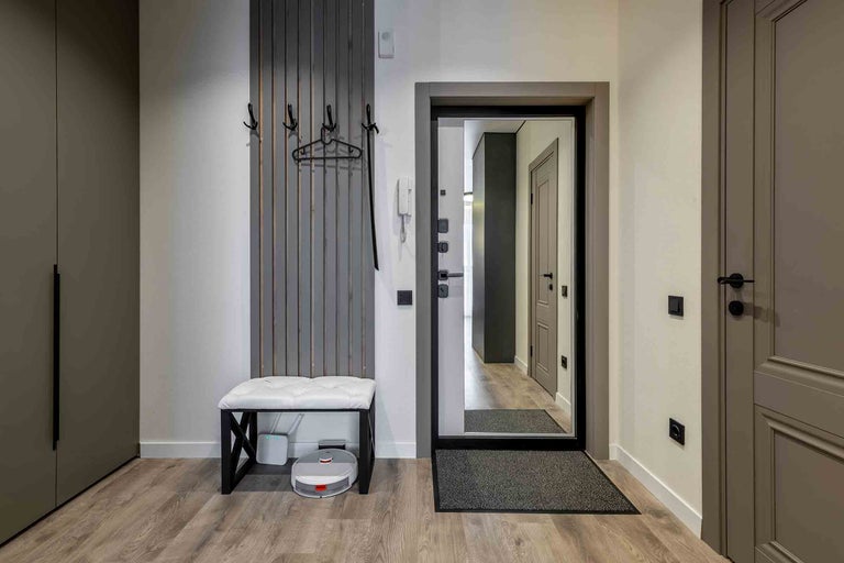 Eingangsbereich mit Garderobe, Sitzbank, Spiegel und Staubsaugerroboter.