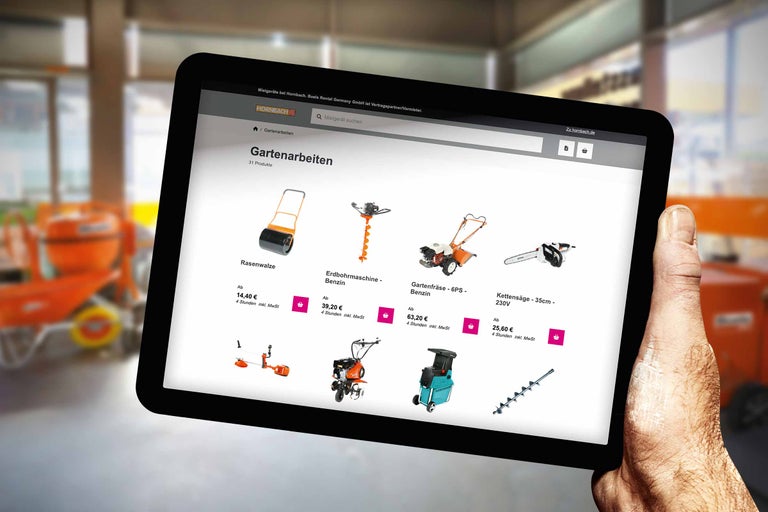 Ein Tablet mit der Hornbach Webseite für Gartenarbeiten wird von einer Hand gehalten. Zu sehen sind Rasenwalze, Erdbohrmaschine, Gartenfräse und Kettensäge.