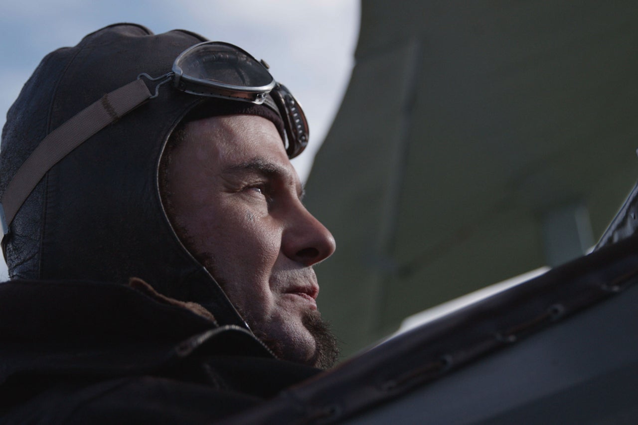 Mann mit Fliegerhaube und Brille blickt in die Ferne