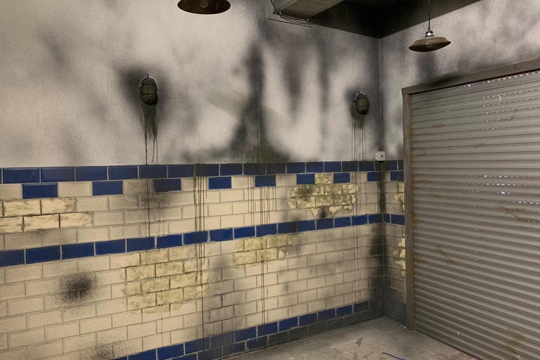 Szene mit gefliesten Wänden, Lampen und Rolltor