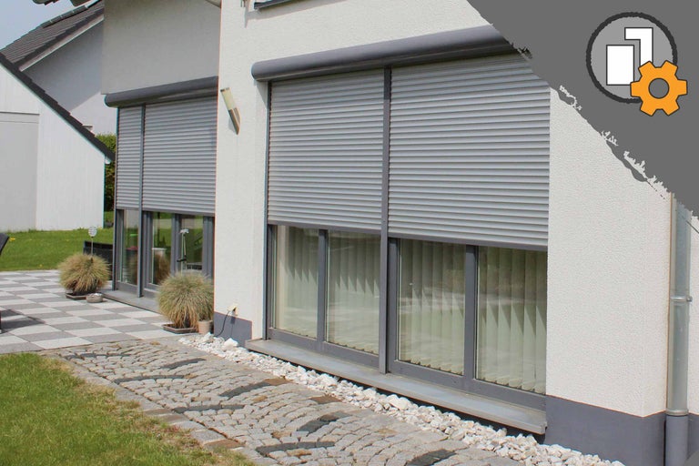 Außenansicht eines Hauses mit heruntergelassenen Rollläden an den Fenstern