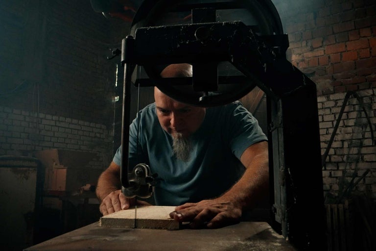 Mann sägt Holz mit einer Bandsäge