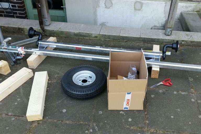 Anhängerachse mit Zubehör, Reifen, Holzbalken und Karton