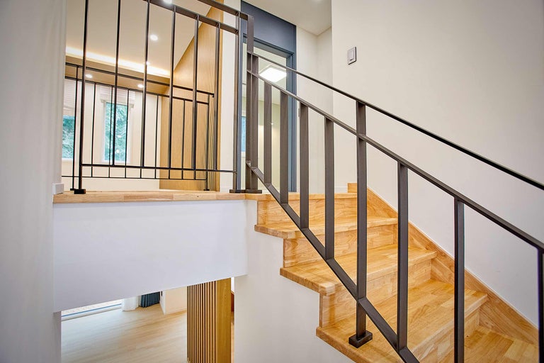 Holztreppe mit Metallgeländer in einem hellen Haus.