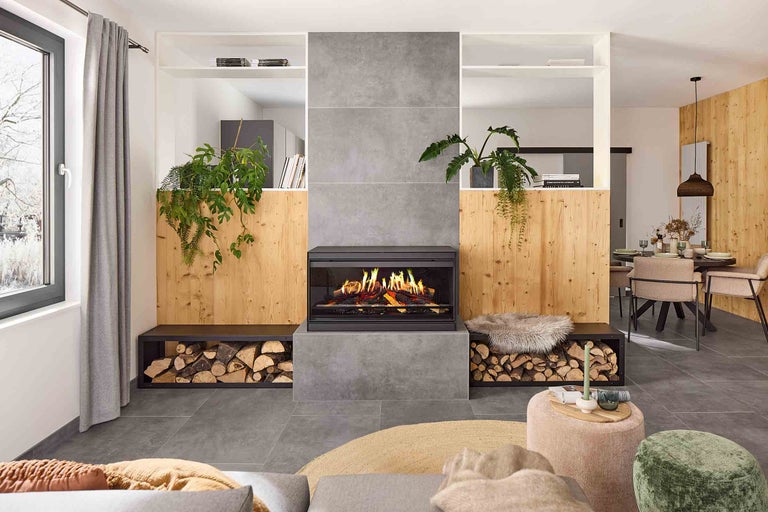 Wohnzimmer mit Kamin, Holzlager, Pflanzen und Sitzgelegenheiten für ein gemütliches Ambiente.