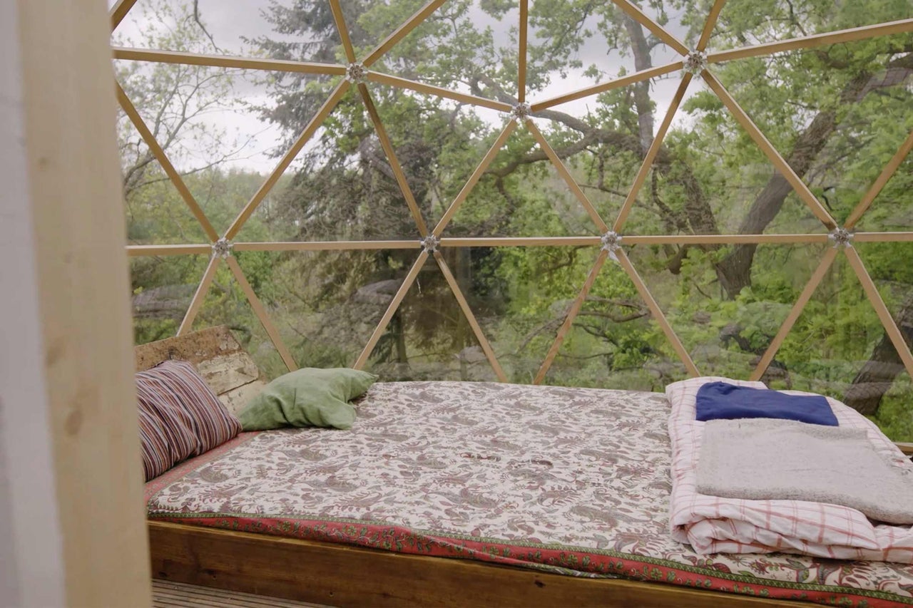 Interieur eines Geodätischen Doms mit Bett und Blick auf die Natur