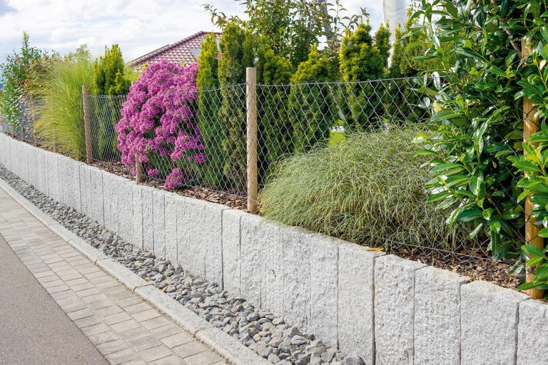 Gartenmauer mit Maschendrahtzaun und Bepflanzung