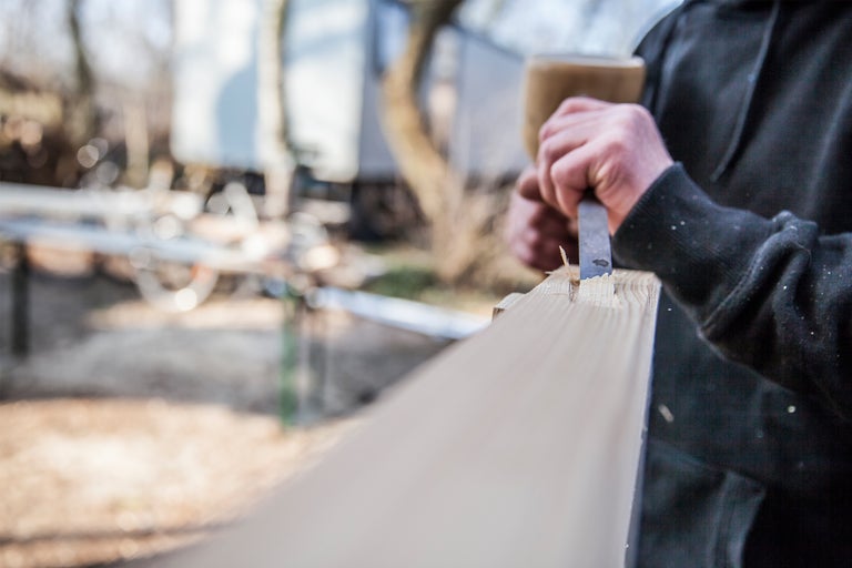Handwerker bearbeitet Holz mit Stecheisen und Hammer