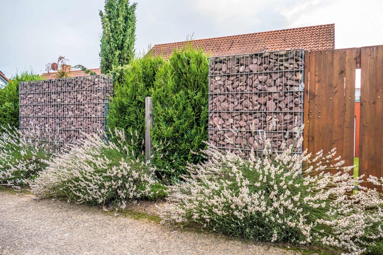 Gabionenzaun mit Steinen und Holzelementen im Garten