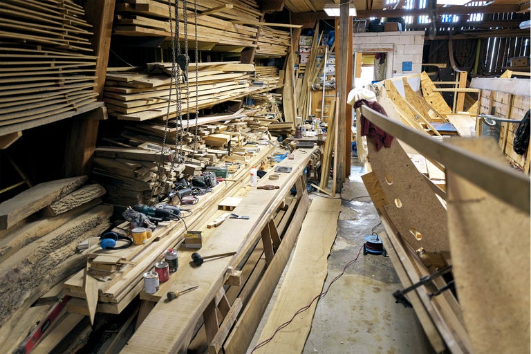 Werkstatt mit Holzstapeln, Werkbank und Werkzeugen