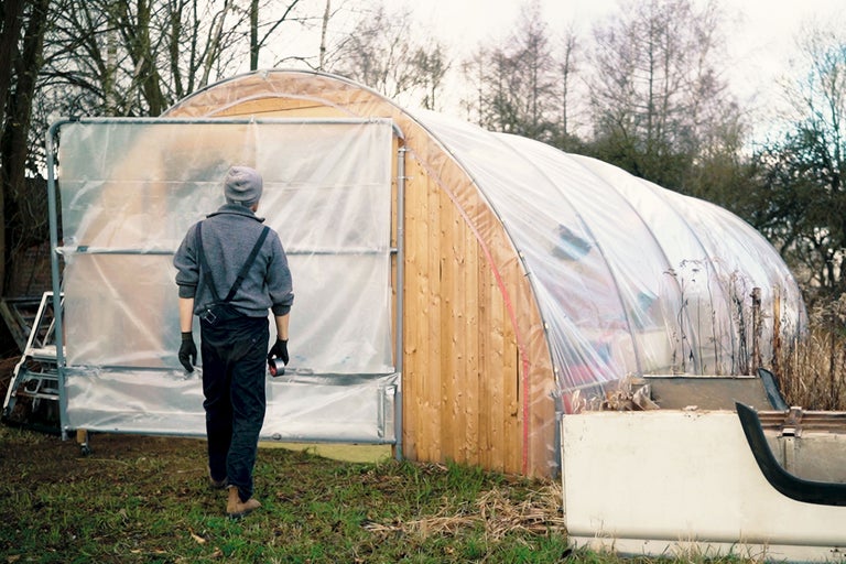 Gewächshaus mit Holzrahmen und transparenter Folie, im Außenbereich