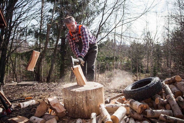 Mann spaltet Holz mit einer Axt im Wald