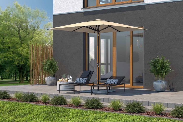 Terrasse mit Sonnenschirm, Liegestühlen und Beistelltisch vor einem Haus