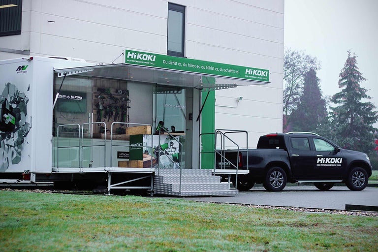 HiKoki Promotion Truck mit HiKoki Pickup Truck geparkt vor Gebäude