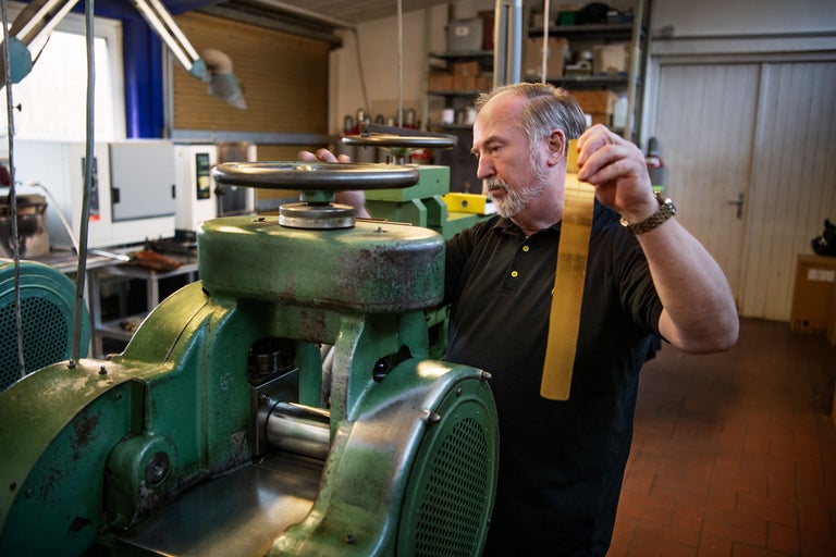 Ein Mann bedient eine Walzmaschine in einer Werkstatt