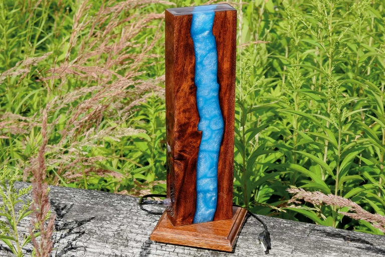 Dekorative Tischleuchte aus Holz und Kunstharz vor Pflanzen