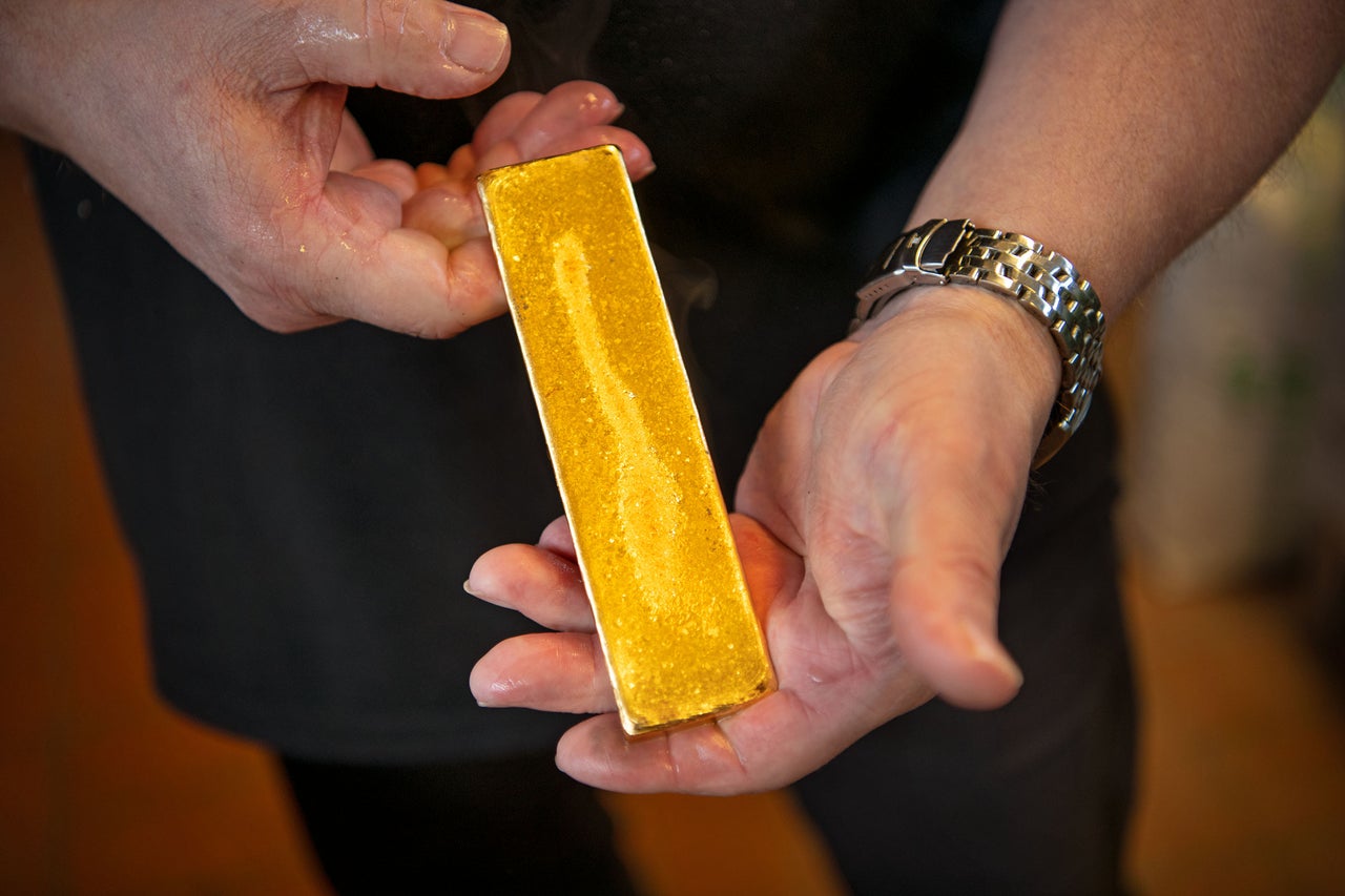 Eine Person hält einen goldenen Barren in den Händen.