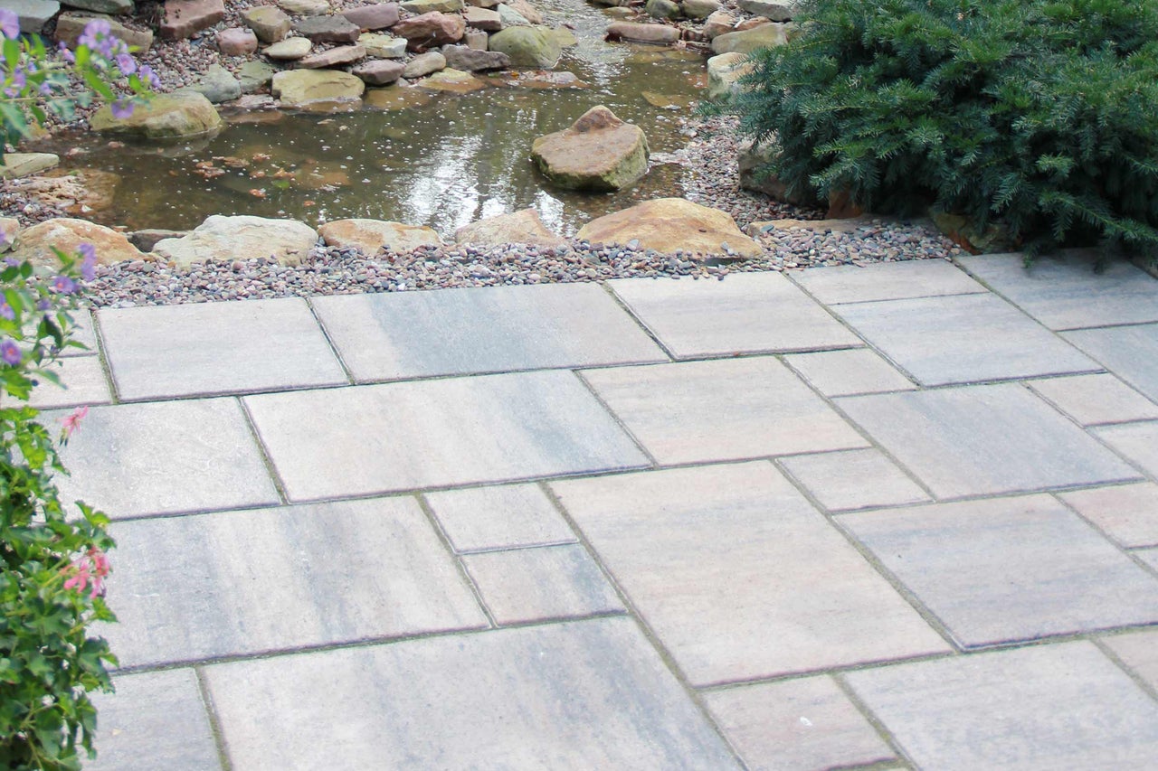 Gartenlandschaft mit Teich und verlegten Pflastersteinen