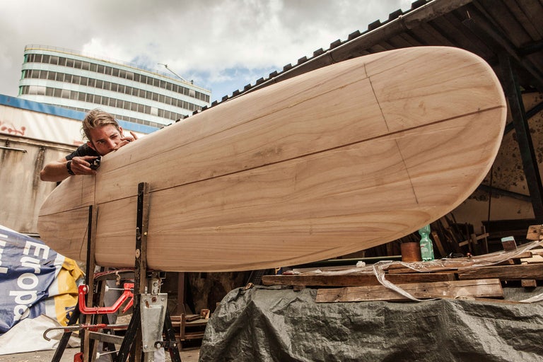 Mann, der ein Holzsurfbrett bearbeitet