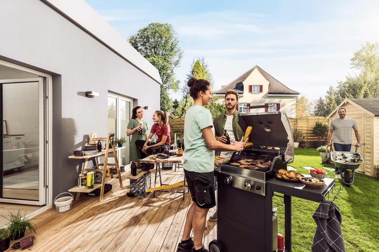 Szene im Garten mit Grillparty auf der Terrasse, Grill, Tisch und Werkzeugwagen