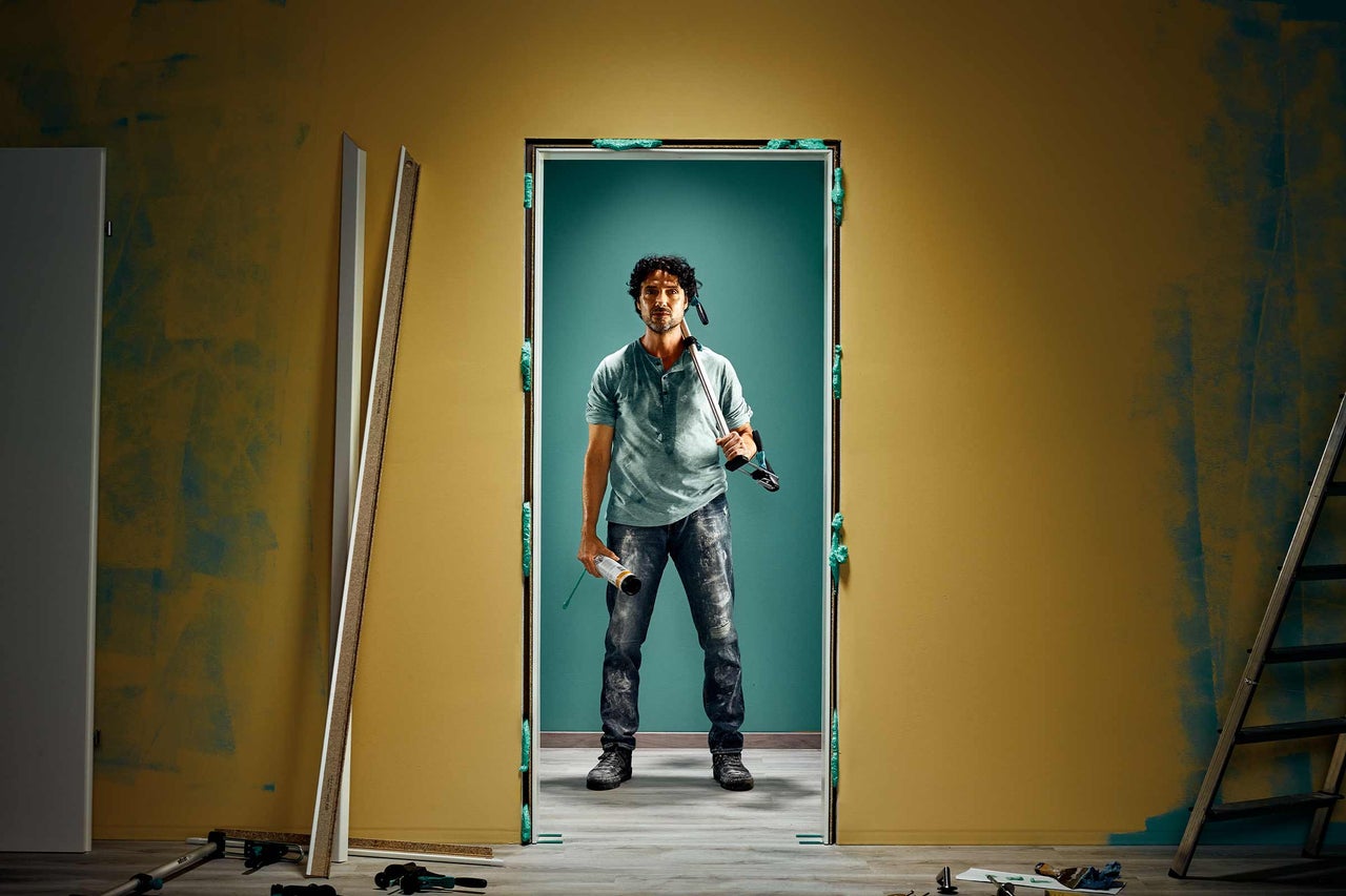 Handwerker montiert Türzarge mit Bauschaum in renovierungsbedürftigem Raum