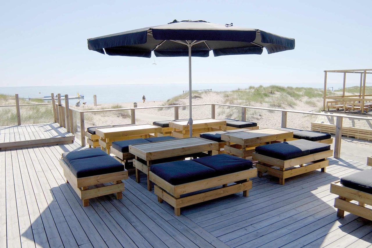 Außenbereich mit Holzboden, Sonnenschirm und Sitzgruppen mit Polstern