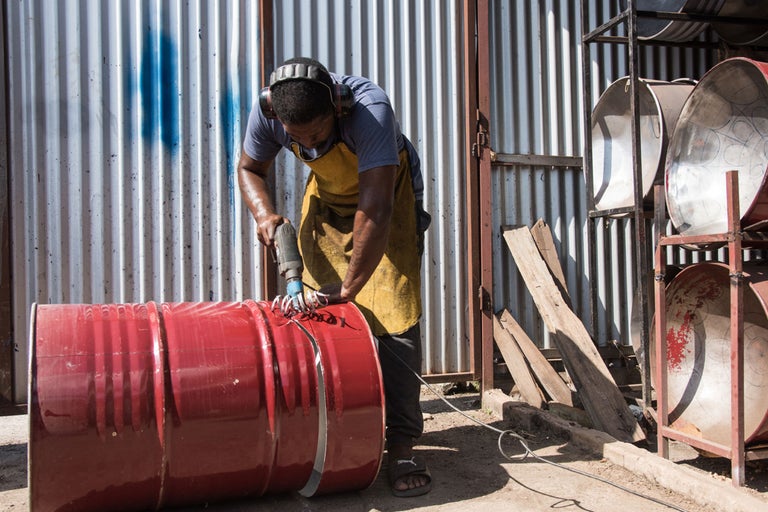 Mann schneidet rotes Metallfass mit einem Trennschleifer.