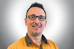 Porträt eines Mannes mit Brille und orangefarbenem Hemd