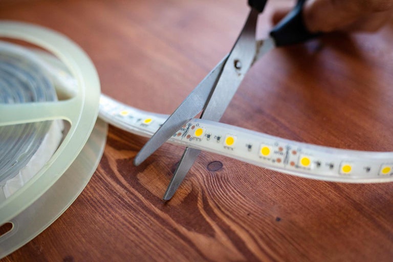 Schere schneidet LED Streifen auf einer Rolle
