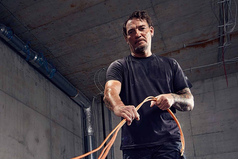 Elektriker hält Elektrokabel in einem Rohbau