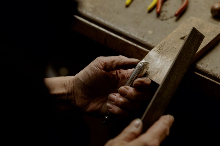 Nahaufnahme von Händen, die mit einer Feile ein Metallstück bearbeiten