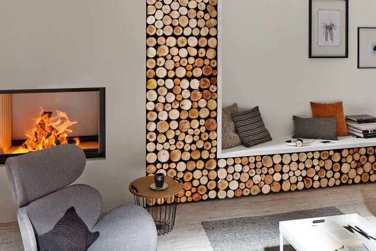 Wohnzimmer mit Kamin, Sessel, Beistelltisch und Wandpaneelen in Holzoptik.