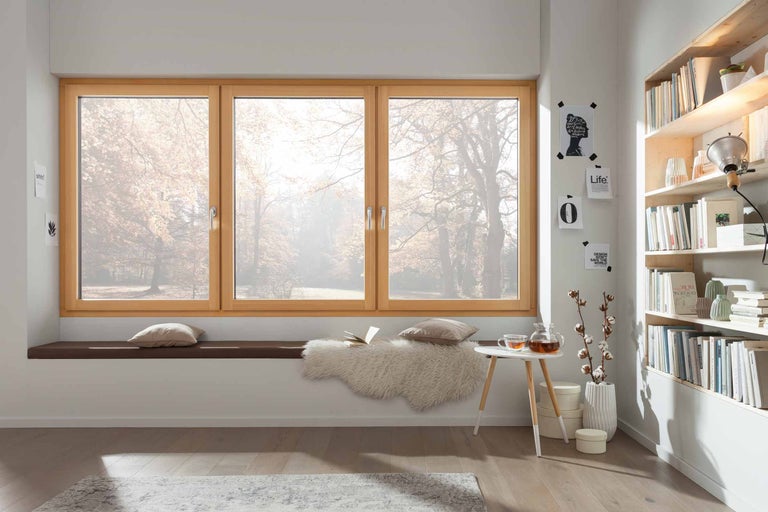 Helle Raumszene mit Holzfenster, Sitzbank, Kissen, Teetisch und Bücherregal für gemütliches Wohnen.