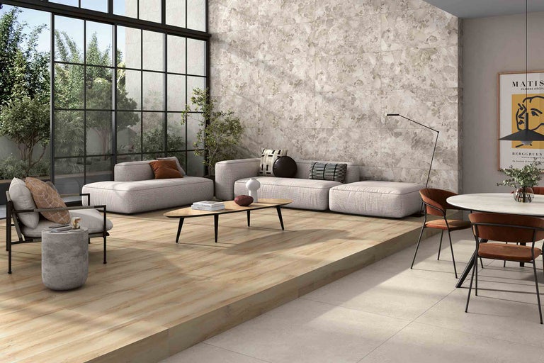 Heller Wohnraum mit Fliesenboden in Holzoptik, Sitzbereich und grosser Fensterfront.