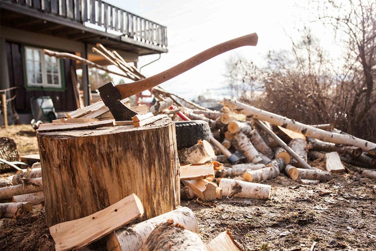 Axt steckt in einem Holzscheit, umgeben von Brennholz.