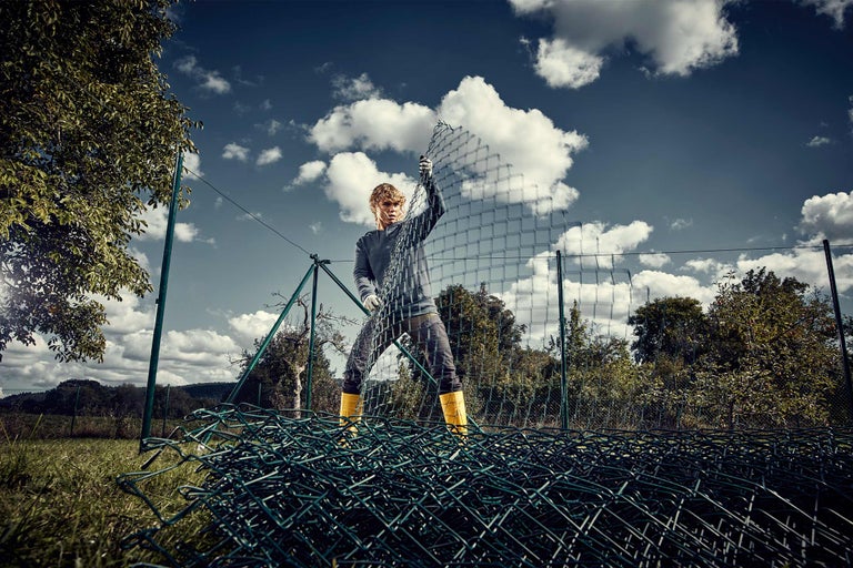 Eine Person installiert einen Maschendrahtzaun im Garten.