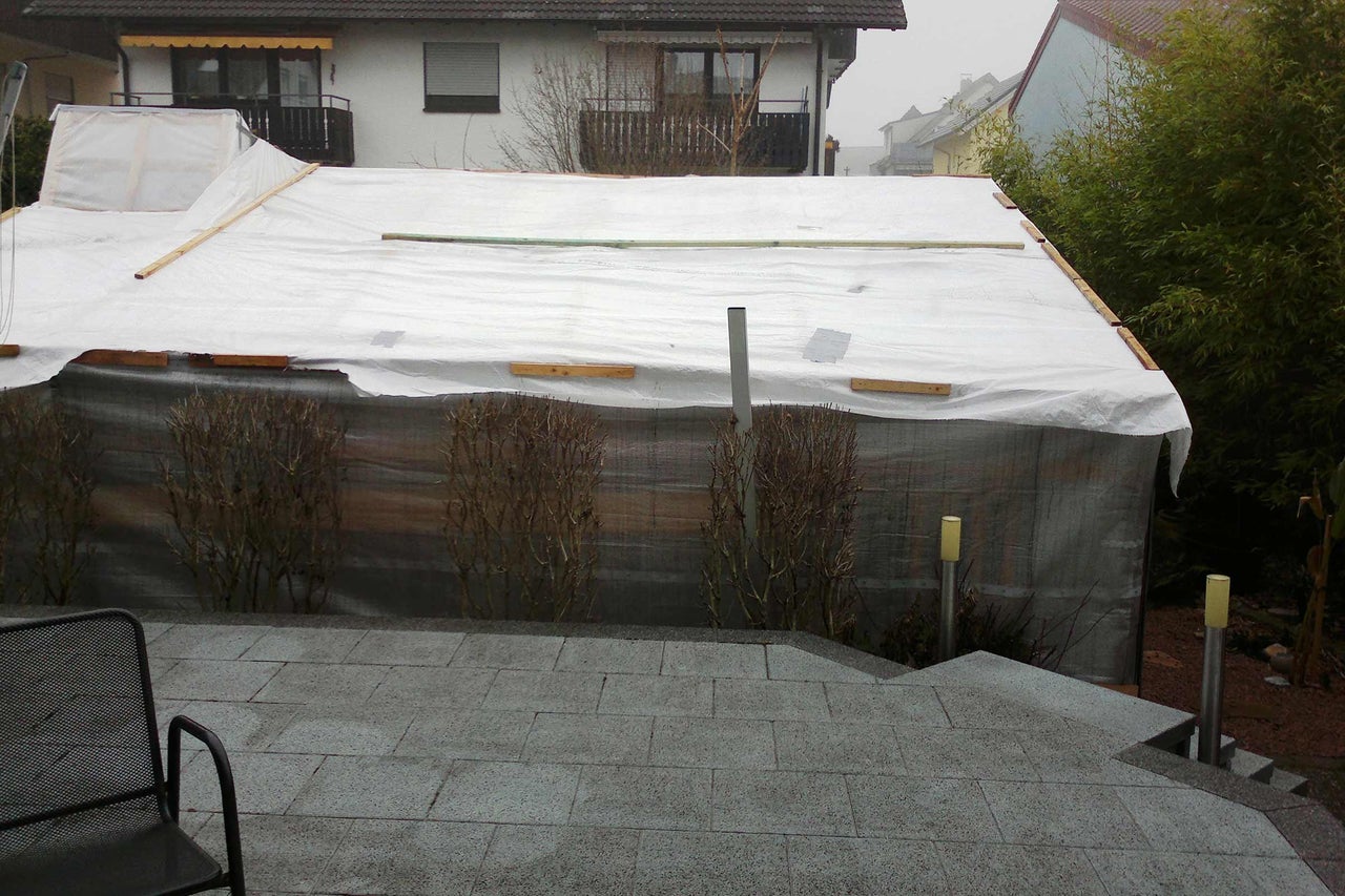 Abgedeckter Pool im Garten mit Plane und Holzkonstruktion.