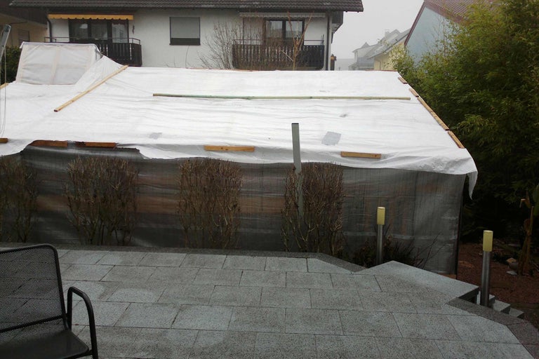 Abgedeckter Pool im Garten mit Plane und Holzkonstruktion.