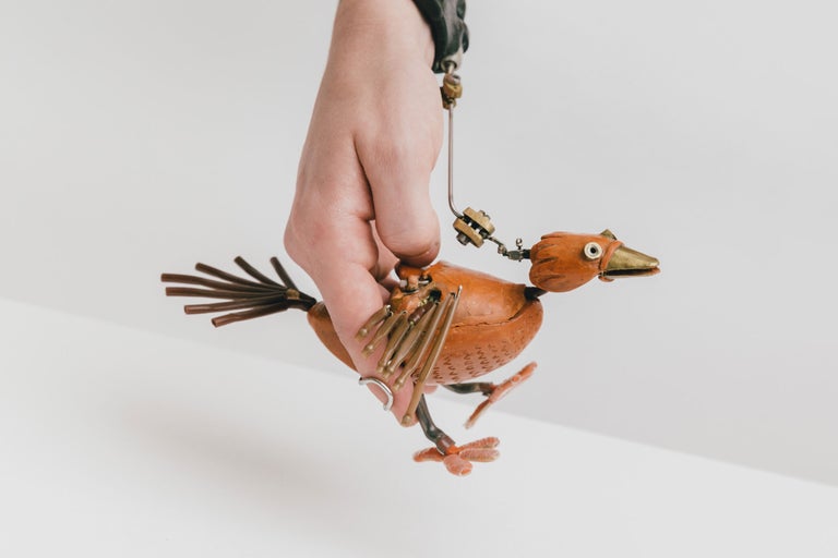 Hand hält eine dekorative Vogel-Figur aus Metall.