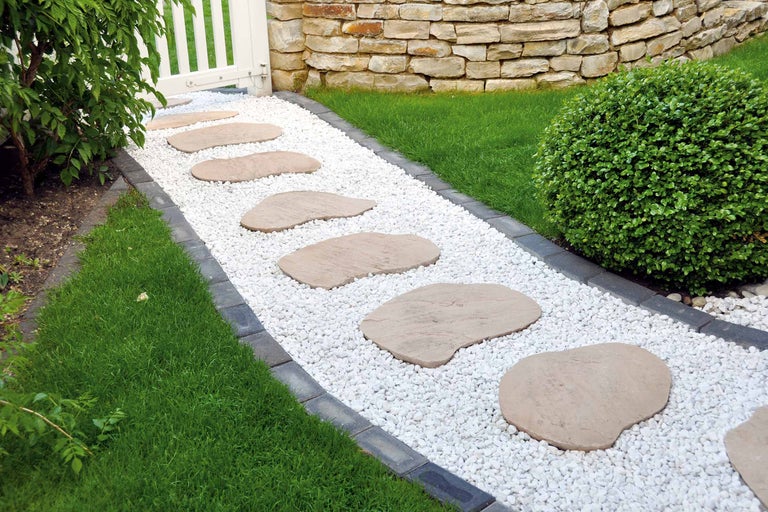 Gartenszene mit Kiesweg, Trittplatten, Rasen und Steinmauer
