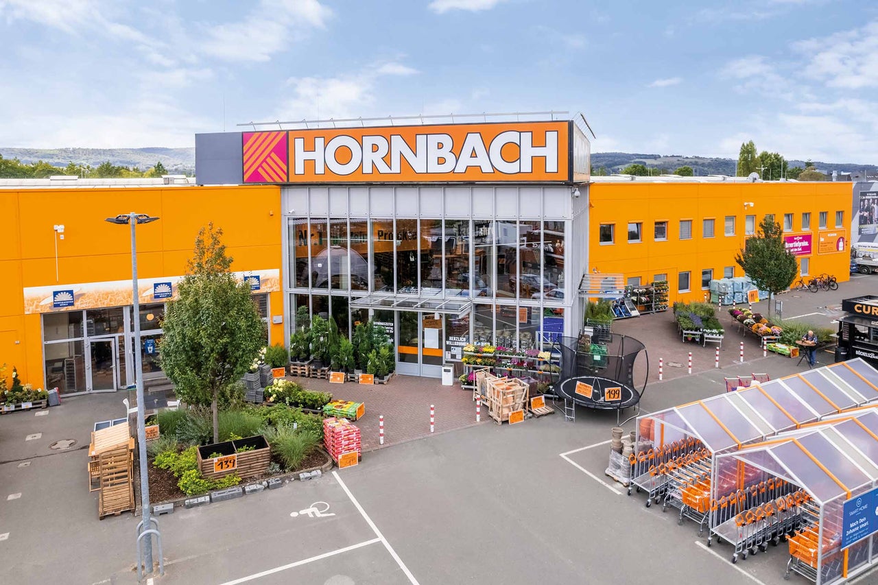  Außenansicht eines Hornbach Baumarktes mit Eingangsbereich und Gartenartikeln. 