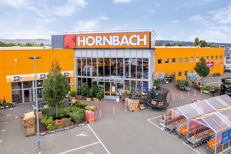 Außenansicht eines Hornbach Baumarktes mit Eingangsbereich und Gartenartikeln.