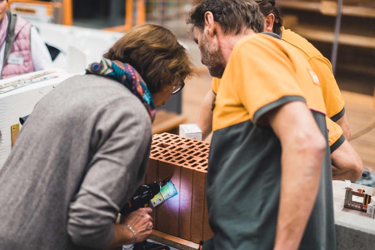 Personen beim Anbringen einer Befestigung an einem Ziegelstein mit einem Werkzeug