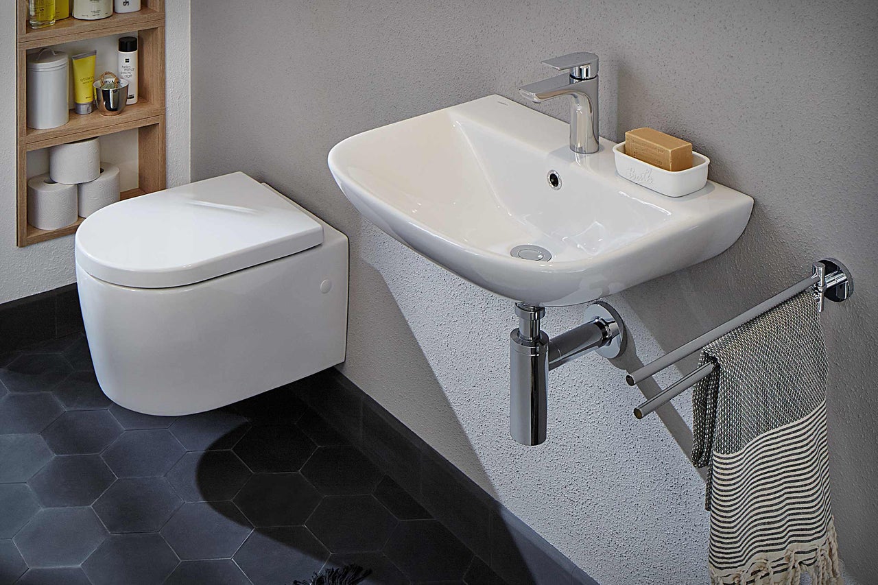 Badezimmer mit wandhängendem WC, Waschbecken, Handtuchhalter und Ablage