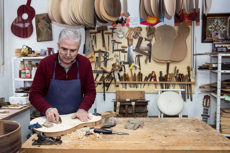 Ein Gitarrenbauer bearbeitet in seiner Werkstatt eine Gitarre.